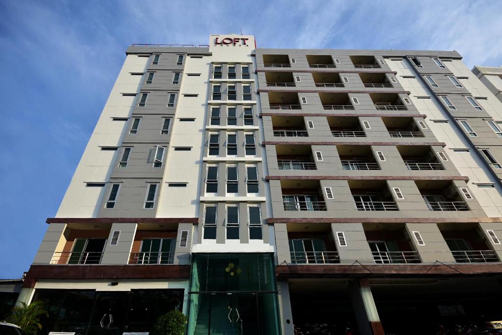 un edificio blanco alto con un cartel de hotel en LOFT Salaya, en Salaya