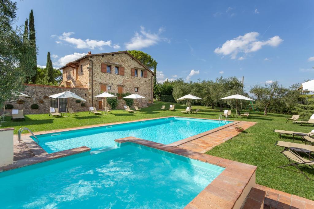 an outdoor swimming pool in front of a building at Fattoria Querceto in Tavarnelle Val di Pesa
