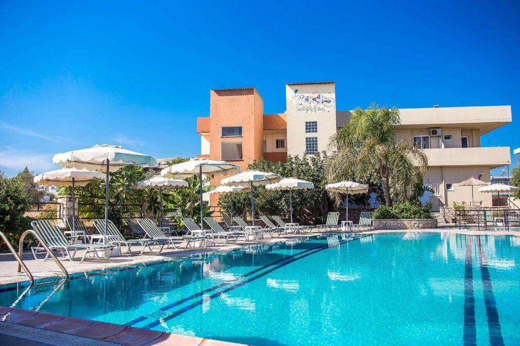 a swimming pool with chairs and umbrellas in front of a hotel at Vickys Studios Faliraki in Faliraki