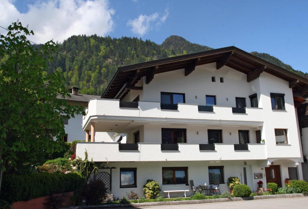 a white building with a mountain in the background at Ferienwohnung Kreidl in Schlitters