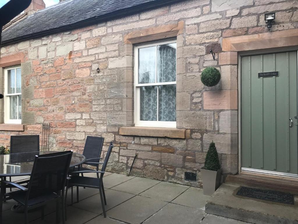 un patio con mesa y sillas frente a un edificio de ladrillo en The Sheriffs Lodge, en Dingwall