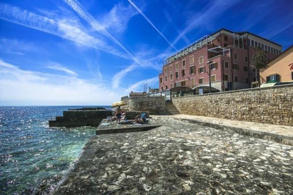 a group of people sitting on the rocks near the water at Rotonda Inn Novigrad in Novigrad Istria