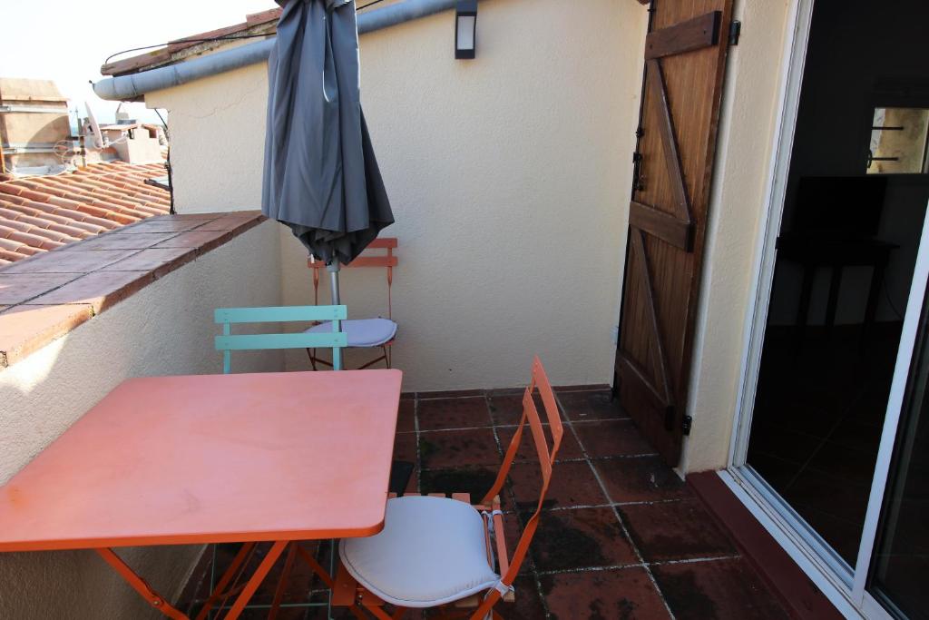 un parasol, une table et une chaise sur le balcon dans l'établissement Maison de village Ramatuelle, à Ramatuelle