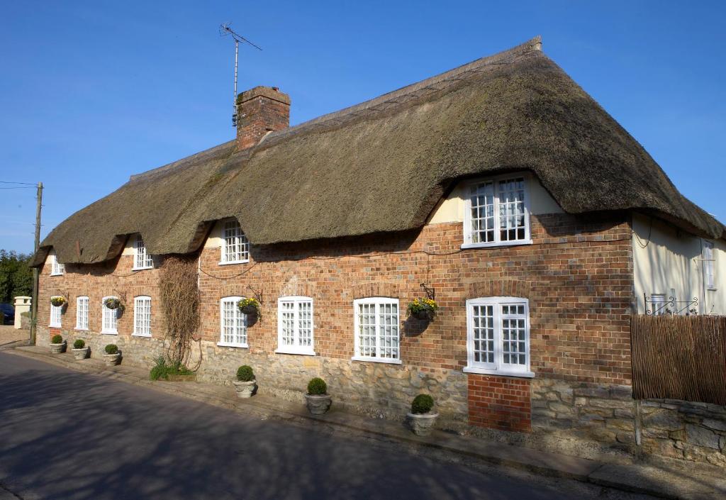 ein altes Backsteingebäude mit einem Strohdach in der Unterkunft Yalbury Cottage in Dorchester