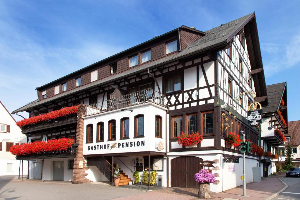 un bâtiment noir et blanc avec des fleurs rouges sur lui dans l'établissement Landgasthof Hotel Hirsch, à Loßburg