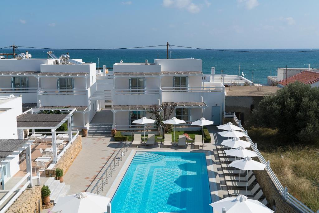a large white building with a swimming pool and umbrellas at Perigiali in Skiros