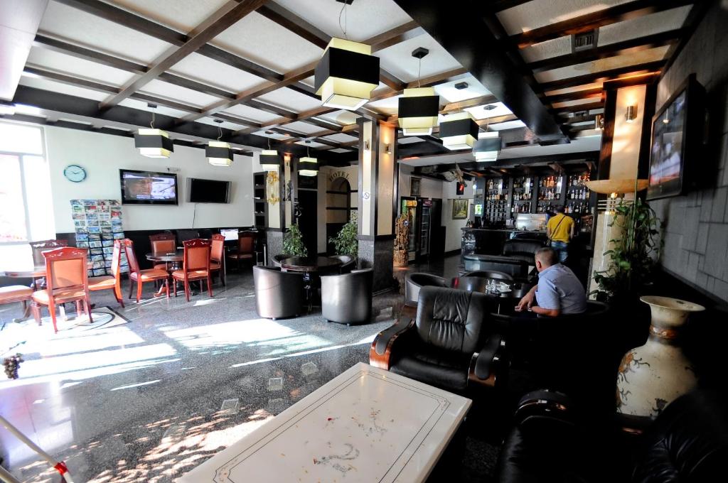 een bar met een man aan een tafel in een kamer bij Hotel Lubjana in Tirana