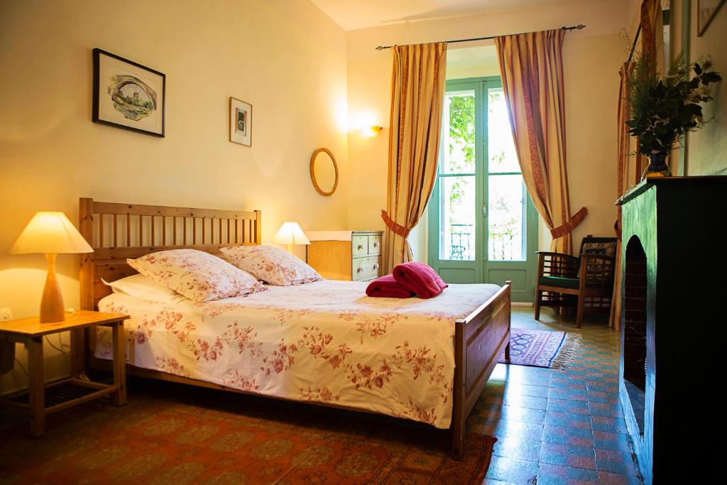 a bedroom with a bed and a large window at The Balcony Gîte - Riverside Lagrasse in Lagrasse