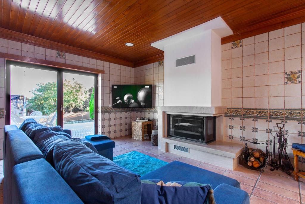 uma sala de estar com um sofá azul e uma televisão em Casa do Casalinho em Avelar