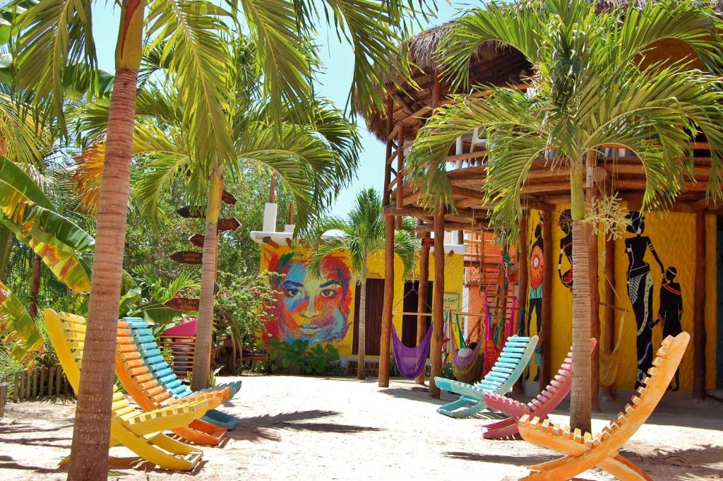a group of chairs and palm trees in front of a building at Tribu Hostel in Holbox Island
