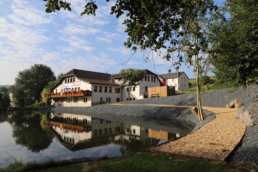 a group of buildings next to a river at Hotel Burg Hof in Burg-Reuland