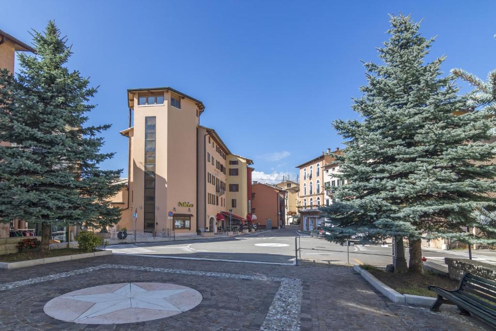 una calle de la ciudad con un árbol y un banco en Hotel Frizzolan en Bosco Chiesanuova