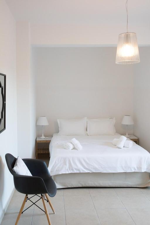 a bedroom with a white bed and a black chair at Niovi Boutique Apartments in Afitos