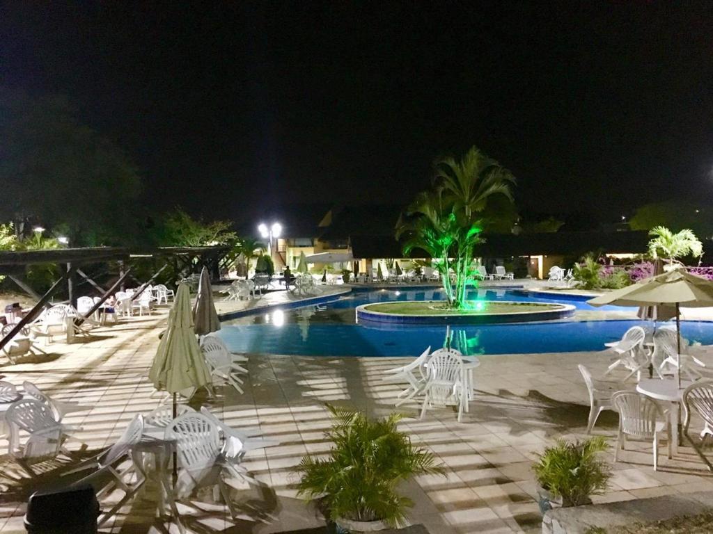 a swimming pool with chairs and umbrellas at night at Winterville Residence - Gravatá in Gravatá