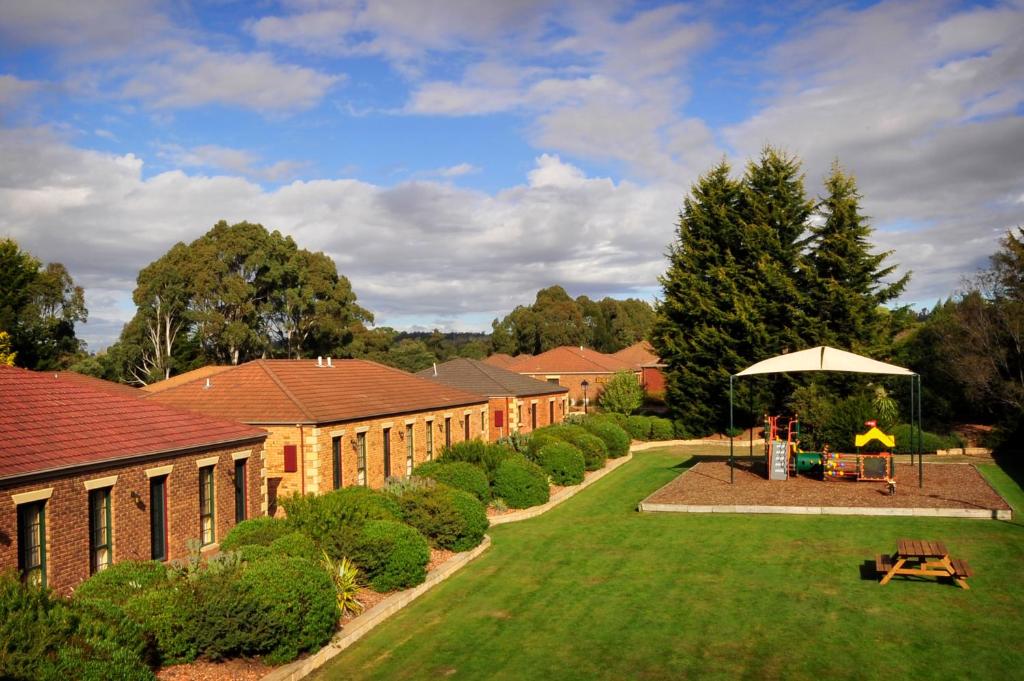 um jardim com um guarda-sol em frente a um edifício em Country Club Villas em Launceston