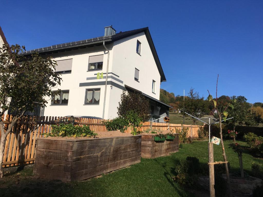 uma casa branca com uma cerca e um quintal em Ferienwohnung an der Linde em Bischofsheim an der Rhön