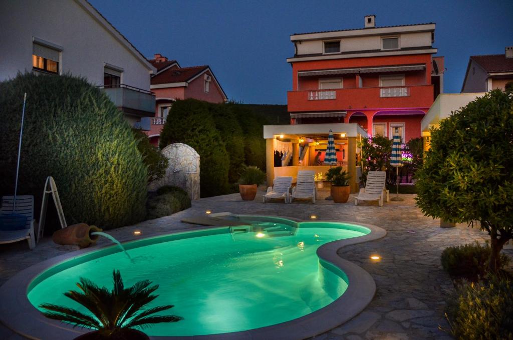 a swimming pool in front of a house at B&B La Perla in Punat