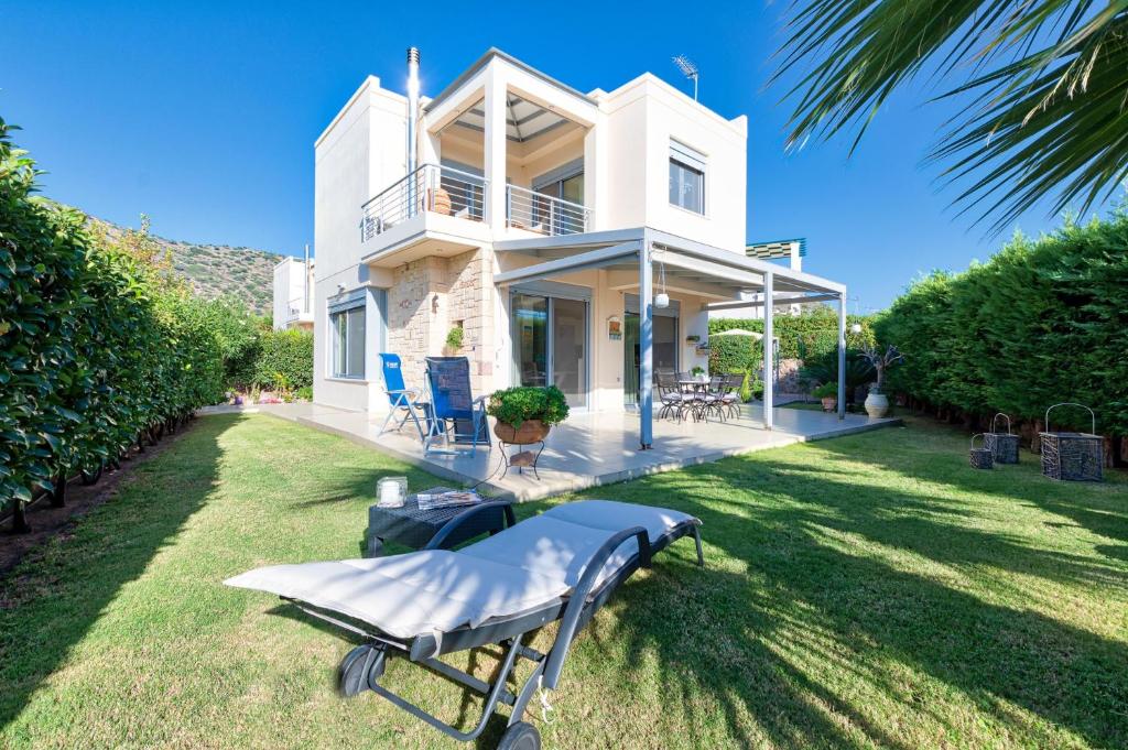 a white house with a table in the yard at Elegant new maisonette near the sea in Aegina Town