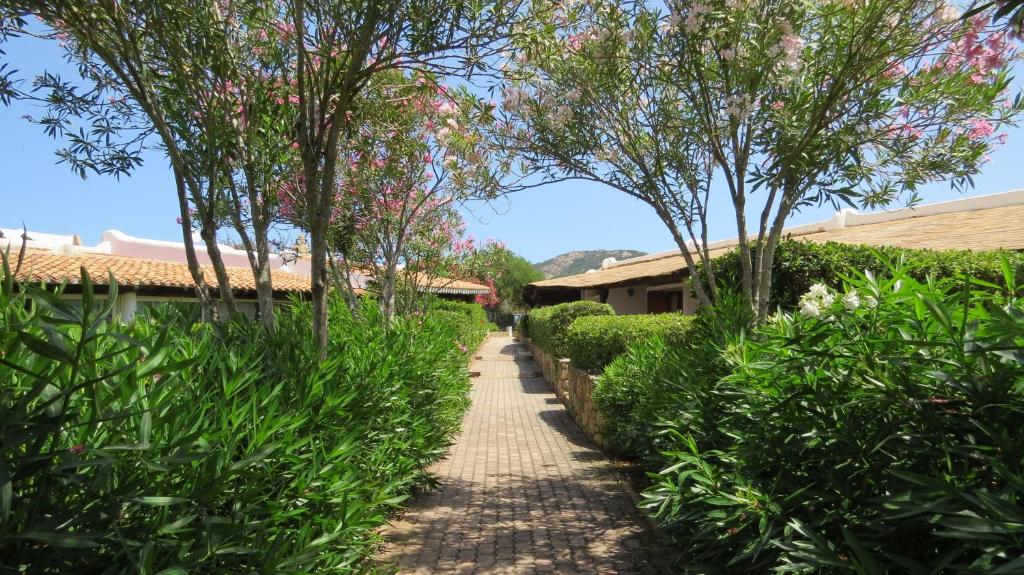 a path through a garden with trees and bushes at Capo Ceraso Family Resort in Costa Corallina