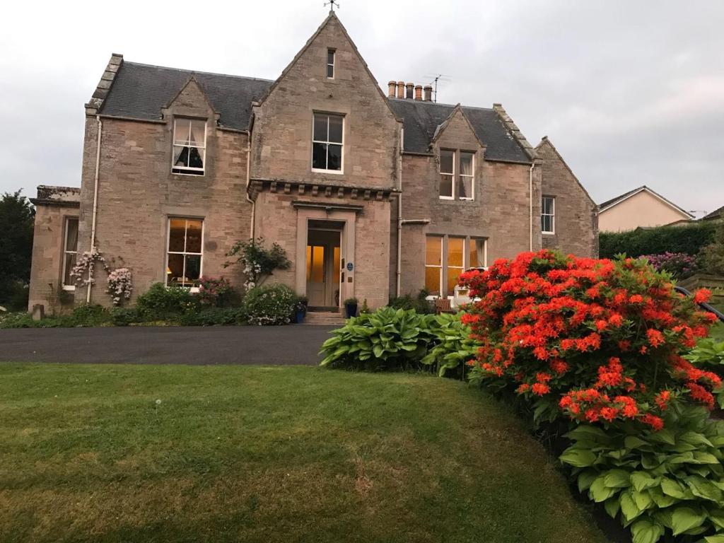 an old house with red flowers in front of it at Allerton House in Jedburgh