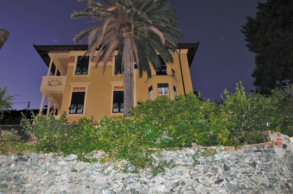 a yellow building with a palm tree in front of it at Villa Margherita in Levanto