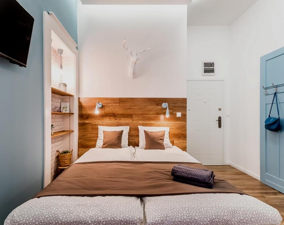 ブダペストにあるThe Blue - studio apartment in the center of Budapestのベッドルーム1室(大型ベッド1台、木製ヘッドボード付)