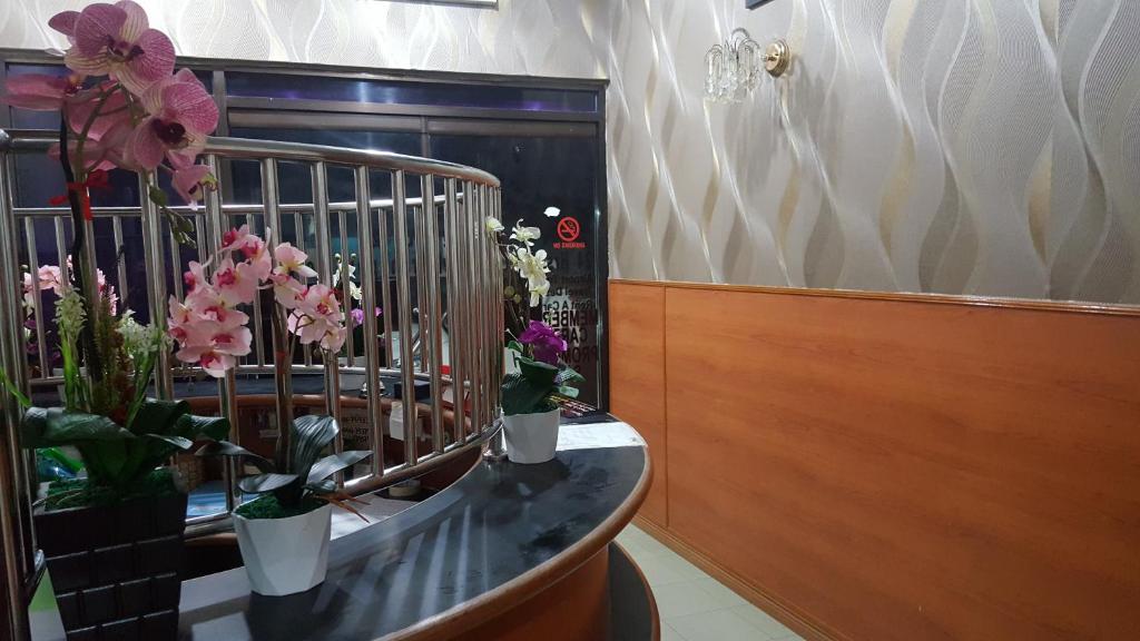 Zimmer mit Blumenvasen auf der Theke in der Unterkunft New Orchid Hotel Tuaran in Tuaran