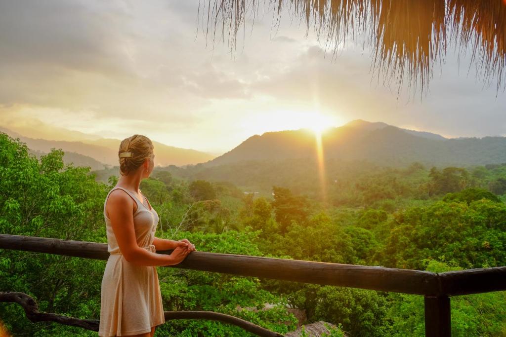 een vrouw op een balkon met uitzicht op de bergen bij Quetzal Dorado Eco-Lodge in El Zaino