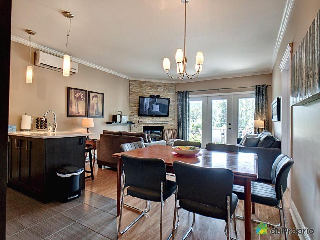 a kitchen and living room with a table and chairs at Condo Le Champlain - 105 in Bromont
