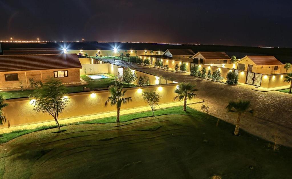 a street with palm trees and lights at night at Jeeda Park Resort in Riyadh Al Khabra