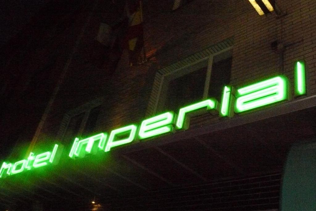 a green neon sign on the side of a building at Hotel Imperial in Wuppertal