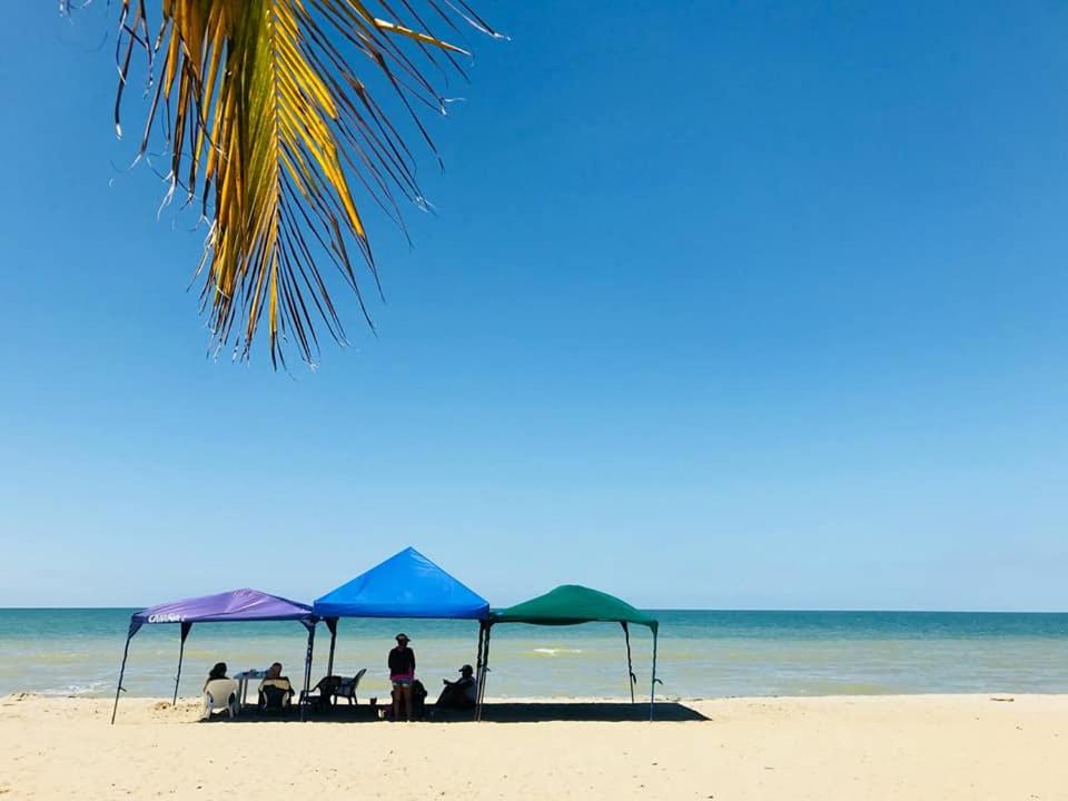 un grupo de personas sentadas bajo sombrillas en una playa en Espectacular cabaña en Coveñas - Sucre, Frente al mar!!!, en Coveñas