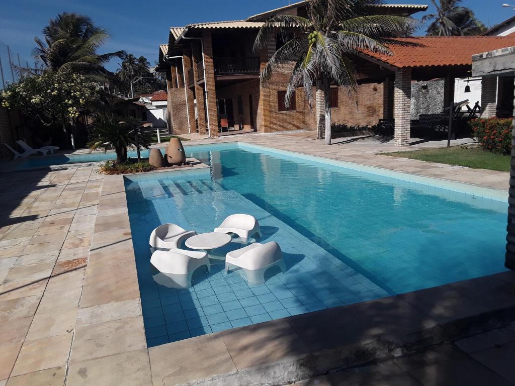 a swimming pool with two white chairs and a swimming pool at Vila Orazio in Prainha