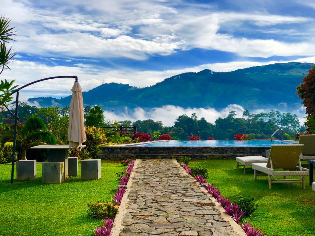 a garden with a pool and a table and an umbrella at Elegant Hotel in Kandy