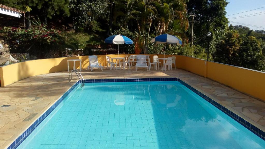 uma piscina com cadeiras e guarda-sóis num pátio em Condomínio Vila Paradiso em Serra Negra