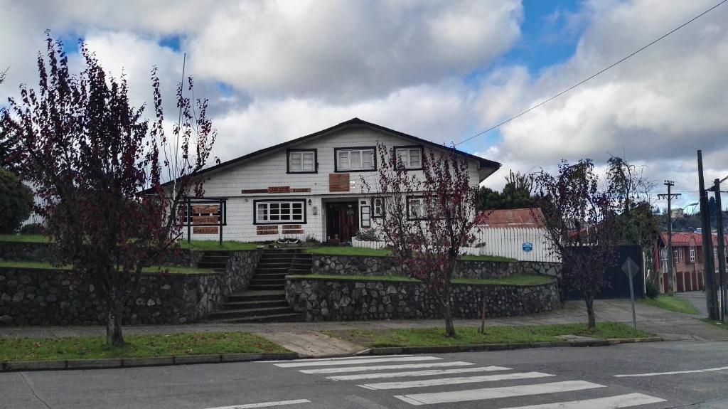 ein weißes Haus auf einer Straße mit einem Fußweg in der Unterkunft Hostal Triwe in Puerto Octay