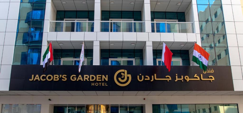 un edificio con un cartello per un hotel con giardino e vasca idromassaggio di Jacob's Garden Hotel a Dubai
