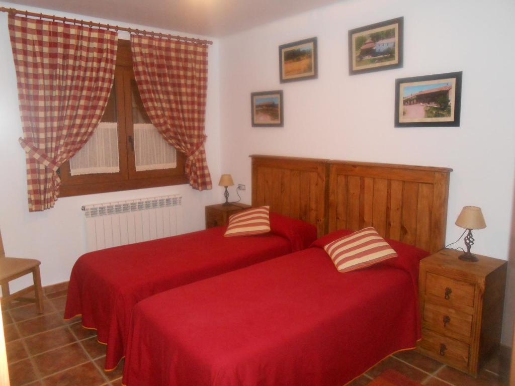 two beds in a bedroom with red sheets at Villa Maria in La Virgen de la Vega