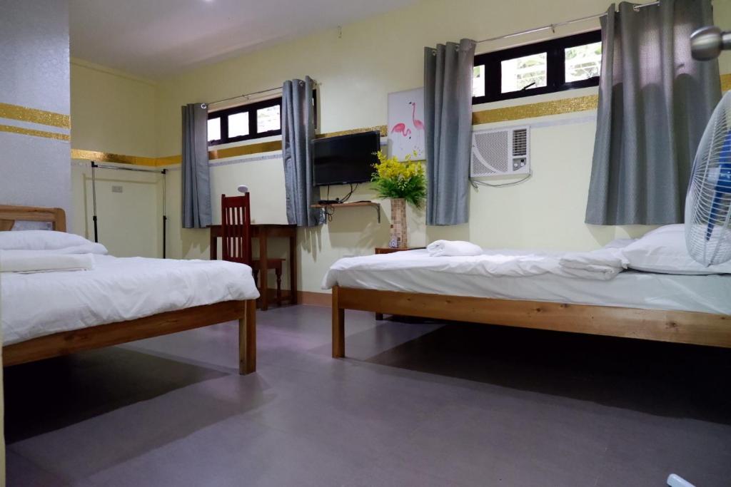 2 Betten in einem Zimmer mit 2 Fenstern in der Unterkunft Nellie's Place in Puerto Princesa