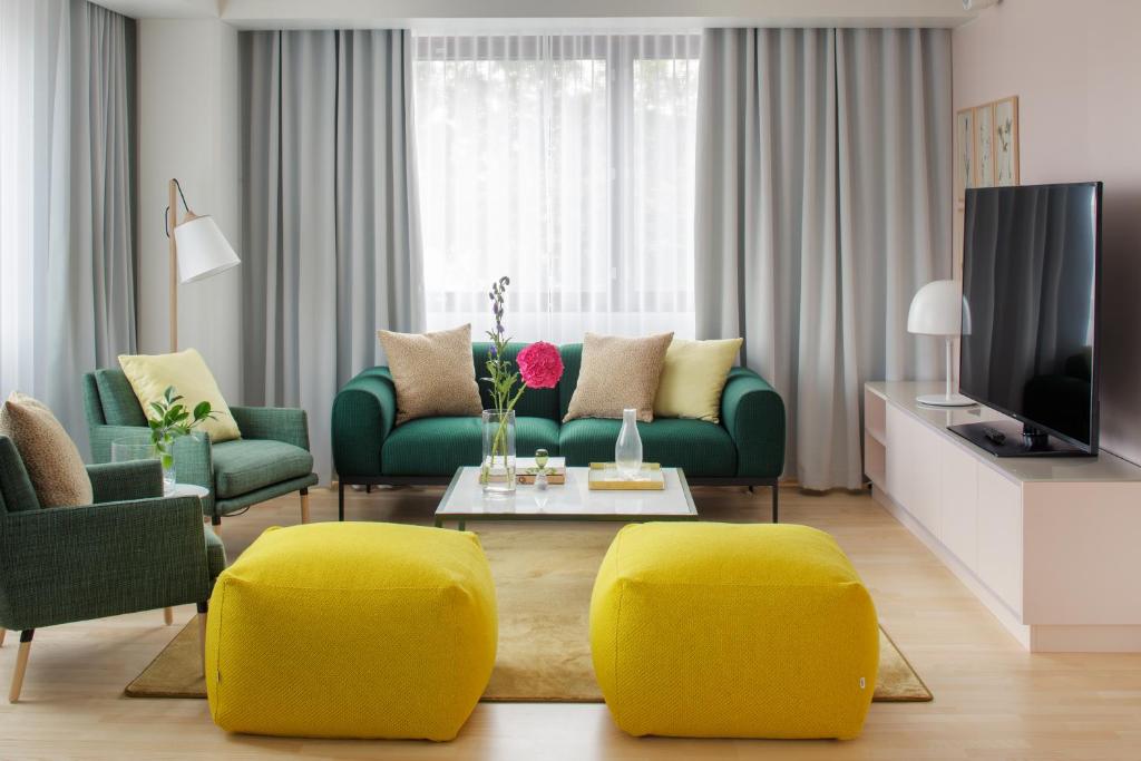 a living room with a green couch and yellow chairs at Original Sokos Hotel Presidentti Helsinki in Helsinki