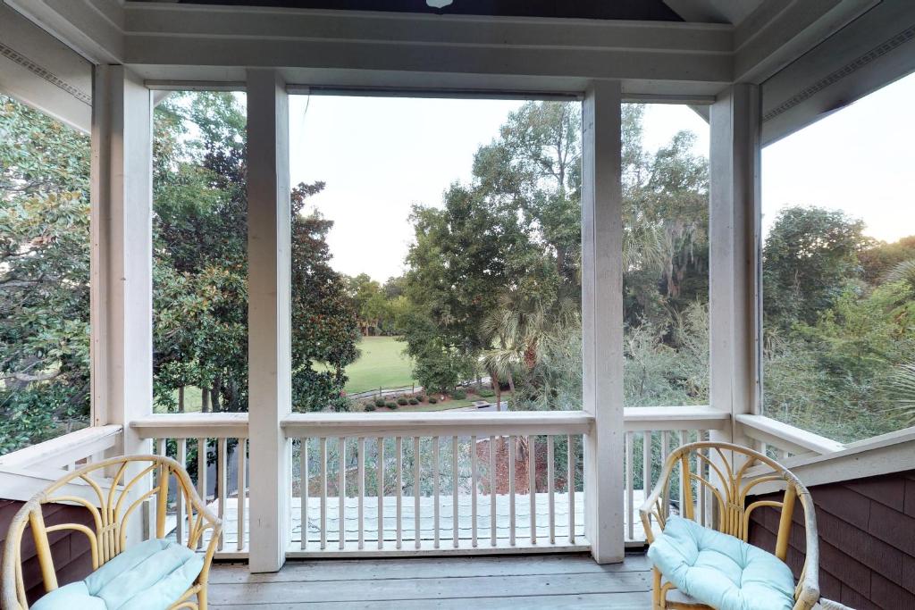 a screened porch with two chairs and large windows at The Green Ocean in Kiawah Island