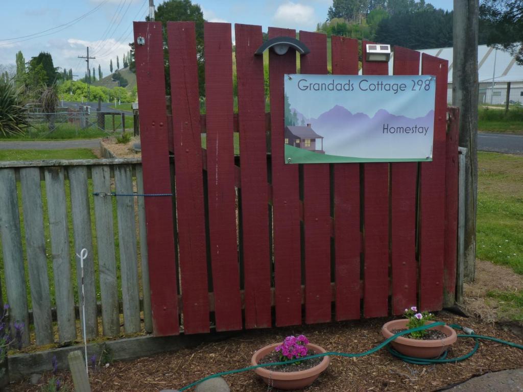 a red gate with two potted plants and a sign at Grandad's Homestay 298 in Taumarunui