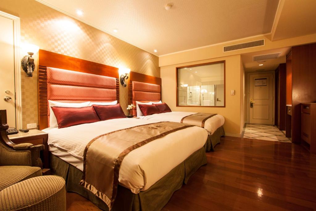 a hotel room with two beds and a mirror at Hualien Charming City Hotel in Hualien City