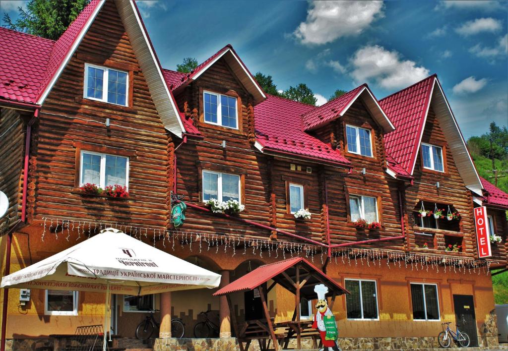 una gran casa de madera con techo rojo en "LiAn" Family Hotel & Restaurant, en Volosyanka