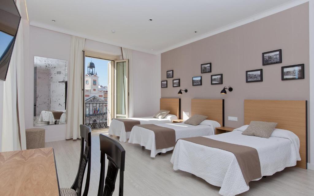 a hotel room with four beds and a table at Hotel Europa in Madrid