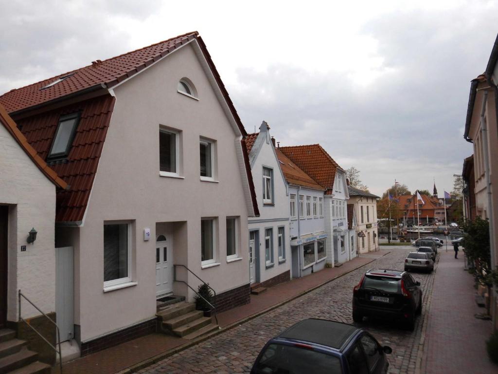uma rua com casas brancas e carros estacionados na rua em Haus am Hafen em Neustadt in Holstein