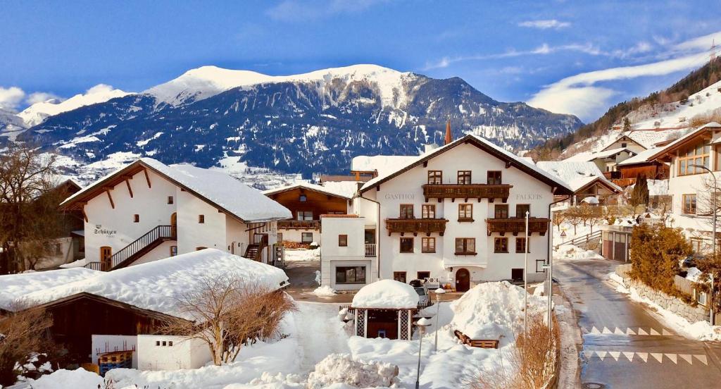 ein schneebedecktes Dorf mit Bergen im Hintergrund in der Unterkunft Gasthof Falkeis in Kauns