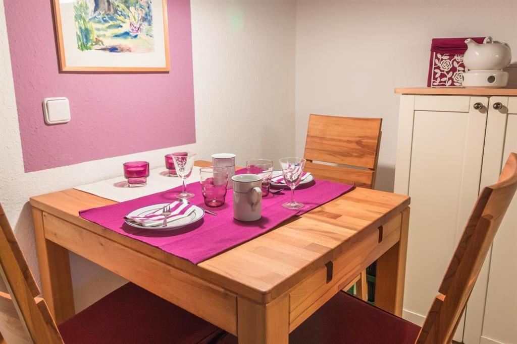 una mesa de madera con copas de vino y platos en ella en Ferienwohnung Küssner, en Kiel