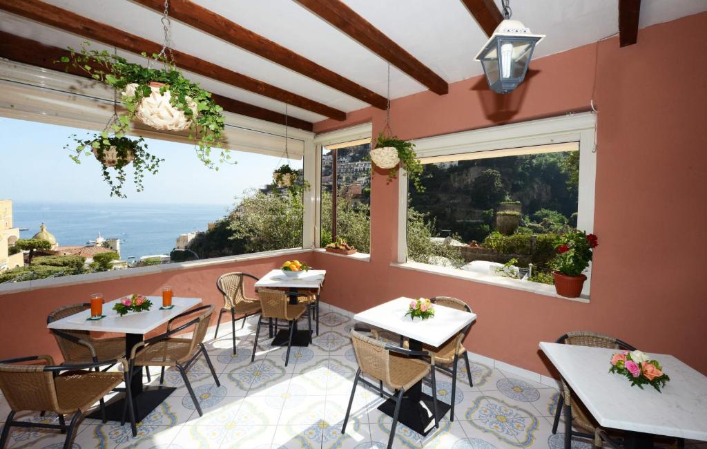 een restaurant met tafels en stoelen en een groot raam bij Villa Maria Antonietta in Positano