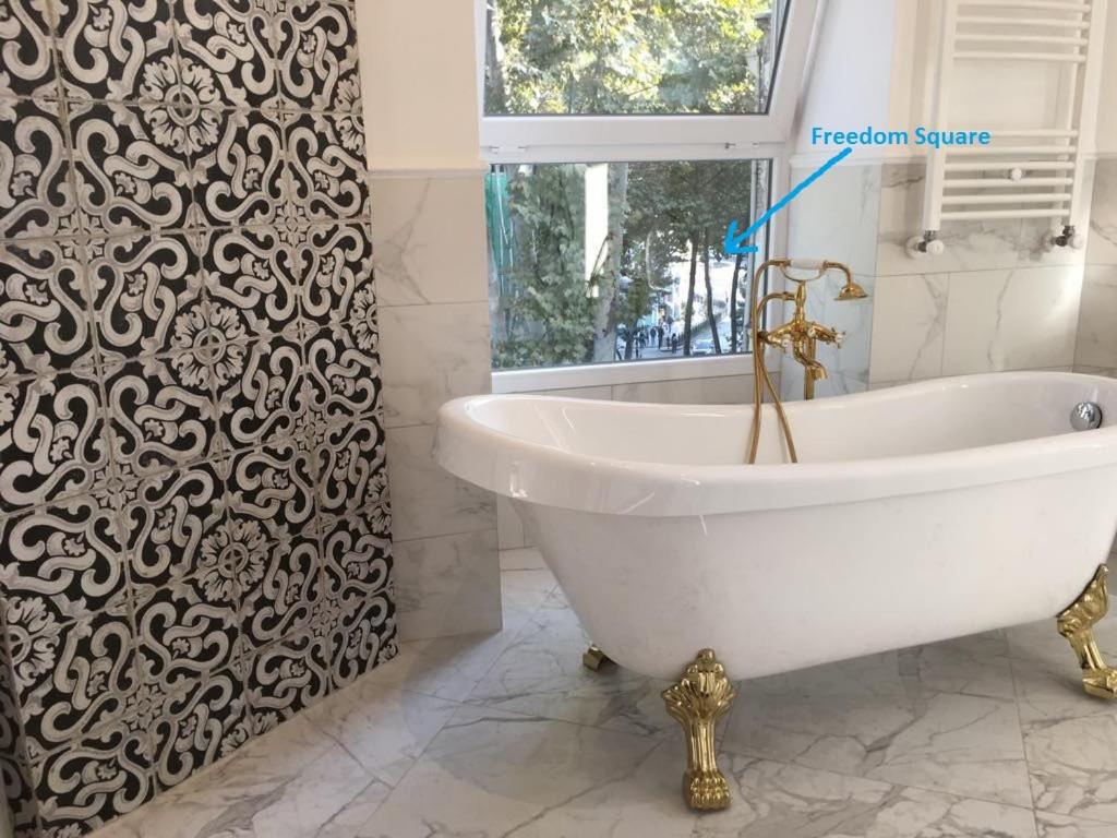 ein Badezimmer mit einer weißen Badewanne und einem schwarz-weißen Duschvorhang in der Unterkunft Deluxe Prince Machabeli Suite in Tbilisi City